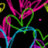 Pixelated abstract composition of interwoven magenta, green, and cyan lines on a black background with scattered pink and yellow fragments.