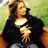 Pixelated static image of a person with long brown hair wearing a black jacket over a white top, seated against a green and orange background.
