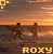 Two figures stand on a beach at sunset with the text 'ROXY' below them; one figure's clothing changes from light to dark between frames.