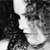 Black-and-white pixelated image showing a partial figure with dark clothing against a light background, featuring a bright white area near the center.
