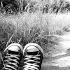 Black-and-white photo of two sneakers on grass with a blurred background, viewed from above.
