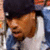 Pixelated close-up of a person with dark hair wearing blue and white clothing, visible from the shoulders up.
