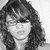 Black-and-white pixelated portrait of a person with shoulder-length wavy hair, bangs, and a neutral expression against a light background.