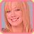 Pixelated portrait of a smiling person with light brown hair and bangs, framed by pink border against gray background.