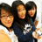 Three people pose together in a group photo with one person holding a white object, displayed in a