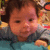 Pixelated close-up of a child's face with brown hair, wearing dark clothing against a blurred background.