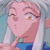 Pixelated close-up of a character with light pink skin, brown eyes, and short light brown hair, wearing a blue and green outfit against a blurred background.