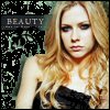 A static image of a person with long wavy blonde hair wearing a black strapless top against a dark patterned background with the word 'BEAUTY' visible.