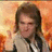 Pixelated static image of a person with shoulder-length dark hair wearing light-colored clothing against warm-toned orange and yellow background.