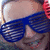 A person wearing blue shutter shades with a pink background and text reading "Dani Dancer" in blue and pink pixelated font.