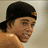 Pixelated close-up of a person with dark hair wearing a black cap, light brown skin tone, and visible shoulder.