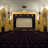 Pixelated theater interior with central screen flanked by golden-brown walls and dark floor, viewed from audience perspective.