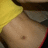 A pixelated close-up of a person's bare torso with a navel, partially covered by a yellow garment on the left and a dark garment on the right.