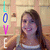 A pixelated image shows a person with long brown hair wearing a white top, holding up a vertical sign that reads 'LOVE' in colored letters.
