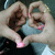 Two hands form a heart shape with fingers, pink light glows at the center of the heart in some frames.