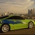 A green sports car with blue accents is positioned on a road against an urban skyline backdrop, partially obscured by pixelated blue and brown artifacts.