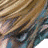A pixelated close-up of a character's face with light brown hair, blue eyes, and a neutral expression against a white background.