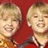 Two pixelated figures with blonde hair smile against a red background, next to blue text on purple.