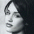 Pixelated grayscale portrait of a person with dark hair, side profile facing left, visible ear, nose, lips, and chin against light background.