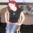 Pixelated image of a person with red hair wearing a black sleeveless top and light blue jeans, standing against an indistinct background.