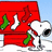 Snoopy stands in front of a red doghouse with Christmas stockings, on a snowy ground under a light blue sky.