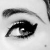 A grayscale close-up of a stylized eye with prominent eyelashes and an arched eyebrow, rendered in pixelated detail.