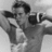 A black-and-white animated sequence shows a shirtless man with dark hair holding binoculars, his head turning slightly left to right across frames.