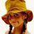 Pixelated image of a person wearing a wide-brimmed straw hat with dark braided hair, brown skin tone, and a neutral expression against a light background.