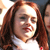 A pixelated close-up of a person with long brown hair wearing a white top, with partial visibility of another figure in the background.