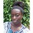 Pixelated image of a person with dark skin wearing a light blue and white striped shirt against a green leafy background.