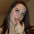 Static pixelated image of a person with long dark hair, light skin tone, and hand near mouth in contemplative pose against brown background.