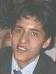 A person in a dark suit and light shirt with a dark tie, showing two facial expressions in a single frame.