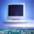 Pixelated static image of a computer monitor with a dark screen, silver frame, and light gray base against a blue gradient background.
