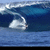 Animated sequence of a surfer riding a large blue ocean wave with white foam, captured from a side view.