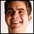 Pixelated close-up of a person's face with brown hair, light skin, and a slight smile, set against a light background.