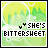 Pixelated green and yellow background with circular patterns, black text reading "SHE'S BITTERSWEET" featuring a small heart symbol above the 'S' in SHE'S.