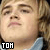 Pixelated close-up of a person's face with closed eyes, light brown hair, and pink lips; black square containing white text 'TOH' in bottom-left corner.