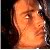 Pixelated close-up of a person's face with light skin tone, visible eye, and dark hair against dark background
