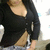 Pixelated close-up of a person wearing black top with visible buttons and light-colored shorts, cropped to show torso and upper legs.