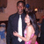 A static image shows a man in a dark suit holding a woman in a pink dress, both with blurred faces, against a dimly lit background with warm tones.