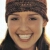 A static pixelated portrait of a person with dark hair tied back, wearing a brown headband and dark clothing against a light background.