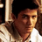 Pixelated close-up of a person with dark hair and light skin wearing a light-colored shirt, set against a dark background with a vertical light stripe.