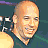 A static image of a bald man in five distinct poses with varying expressions and clothing across different backgrounds.