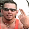 A person in an orange tank top and beaded necklace makes a finger gun gesture with text overlays changing across frames.