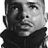 Black-and-white pixelated static icon of a person's face with visible facial features and clothing, rendered in grayscale tones on a transparent background.