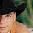 Pixelated image of a person wearing a black cowboy hat with text "KENNY CHESNEY" on the right side against a green background.