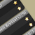 Black and silver diagonal stripes with five glowing yellow-orange squares on a beige background.