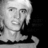 Pixelated grayscale portrait of a person with light hair, neutral expression, and visible neck against dark background.