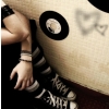 A close-up of a person's arm and hand resting on a large, light-colored object with a circular black-and-white emblem and faint triangular symbols.