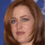 Pixelated close-up of a person with light brown hair against a blue background, showing partial facial features including eyes, nose, and lips.
